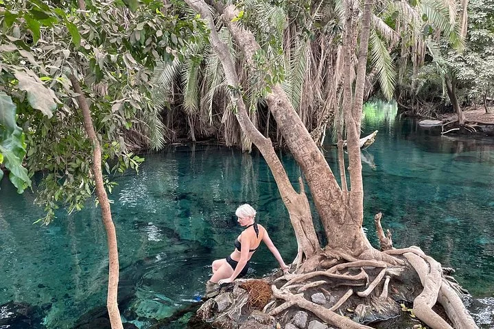 A woman sits by the clear blue water of Chemka Hot Springs.