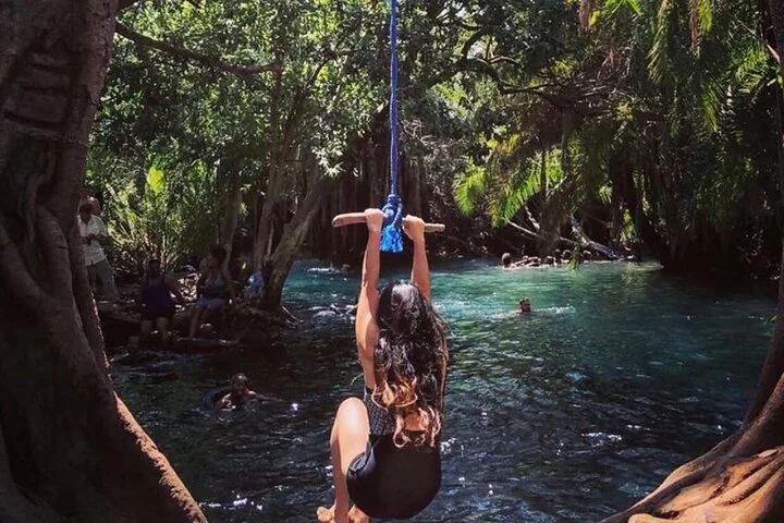 Eine Frau schwingt an einem Seil über dem klaren Wasser der Chemka Hot Springs.